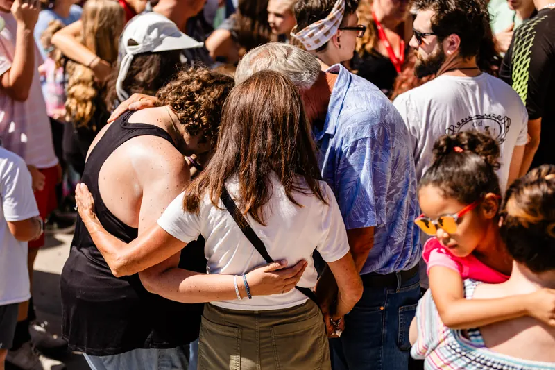 People embrace and pray together in a crowded amphitheater during a morning service.