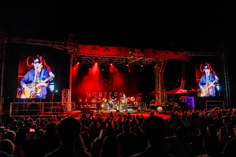 The Horizon stage glows red at night with performers shown on the large side screens above the crowd.
