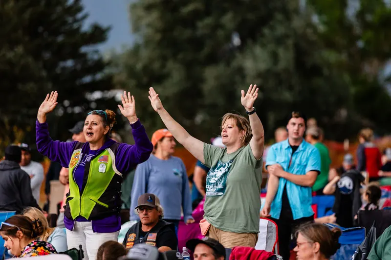 People on the festival lawn raise their hands during an outdoor worship set.